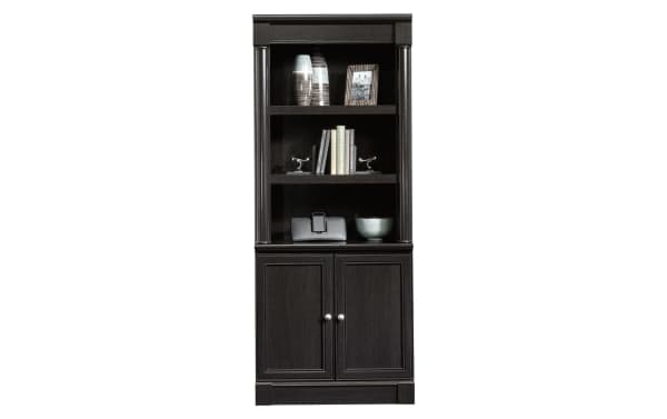 Tall dark wood bookcase with two shelves, decorative items, and a lower cabinet with double doors and silver knobs.