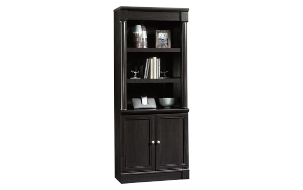 Tall dark wood bookcase with two shelves, decorative items, and a closed cabinet with silver knobs at the bottom, modern style.