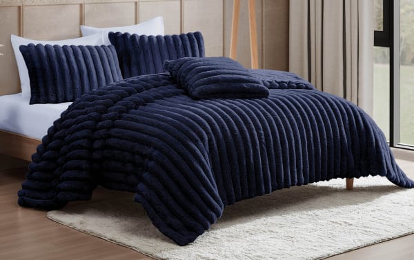 Luxurious navy blue ribbed plush comforter set with matching pillow shams on a modern wooden bed frame, styled in a bright bedroom.