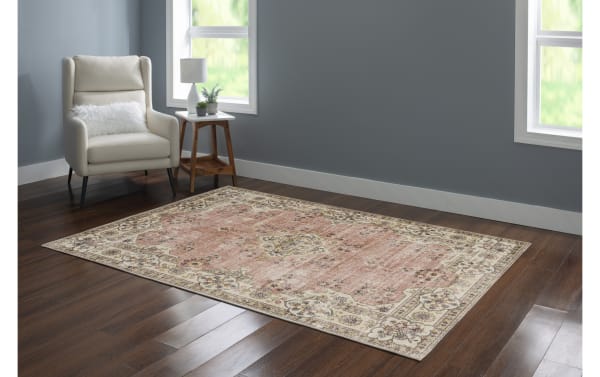 Kinsley 5' x 7' pink traditional washable rug with floral border and medallion pattern, stain-resistant polyester fabric, non-slip backing for high-traffic areas.