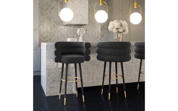 Marne Black Upholstered Bar Height Stool with velvet fabric, birch legs, and gold stainless steel footrest, featuring a contemporary cushioned round seat and backrest.