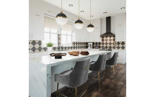 Contemporary Giselle dark gray velvet counter height stools with solid backs, stainless steel legs, and gold-tone handles, set at a marble kitchen island.