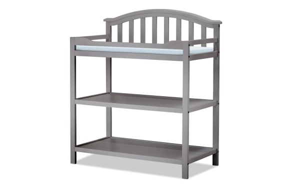 Finlay Gray Changing Table in gray pine solids with transitional style, curved back silhouette, safety belt, and two storage shelves.
