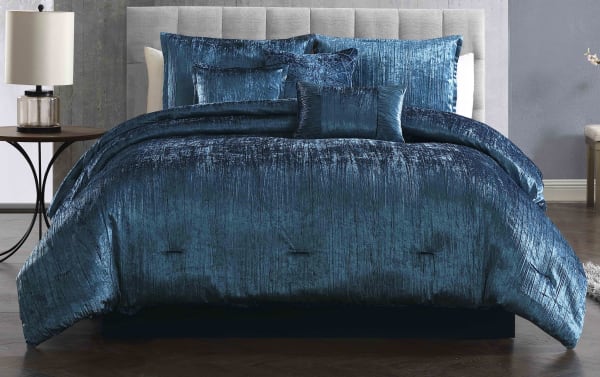 Luxurious navy blue crushed velvet comforter set on a modern bed with matching decorative pillows, featuring a soft, textured fabric and elegant sheen.