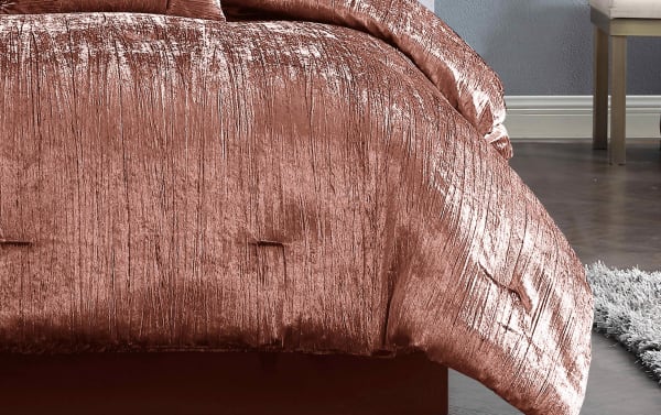 Luxurious crushed velvet comforter in a rich rose gold color with a soft, textured finish, styled on a modern bed frame.