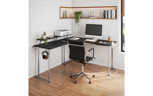 Zuma Silver Adjustable L-Shaped Gaming Desk in black MDF with silver powder-coated steel frame, featuring dual adjustable monitor shelves, cup holder, and headphone hook for versatile gaming or office setups.