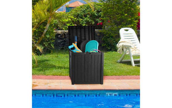 Black Osgood 50 Gallon Outdoor Storage Box in contemporary resin with faux-wood slat design, open lid, holding pool toys by a backyard pool.