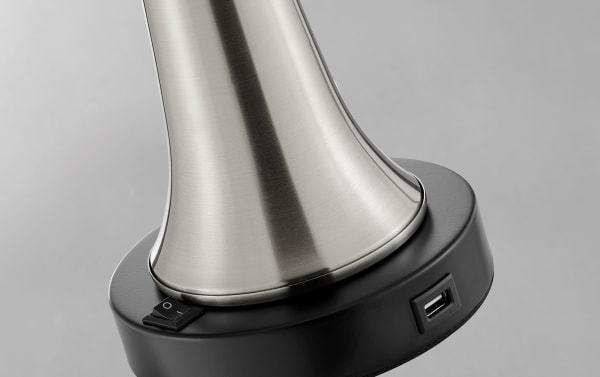 Base of Ferrara brushed nickel table lamp with black switch and built-in USB port, showcasing sleek metal design in contemporary white fabric style.