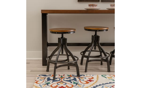 Hadley Brown Backless Adjustable Stool from Hadley collection, featuring industrial steel frame, brown MDF seat, rivet details, and round footrest.