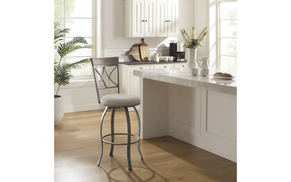 Homer Beige & Pewter Cross Back Bar Height Stool with beige polyester fabric seat, pewter steel frame, lattice backrest, swivel seat, and circular footrest.