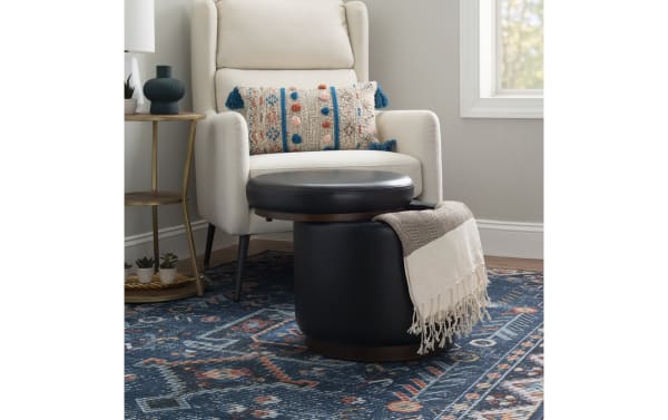 Blaze Black & Brown Faux Leather Storage Ottoman with round cushioned top, black faux leather upholstery, and wood base, ideal for storage and seating.