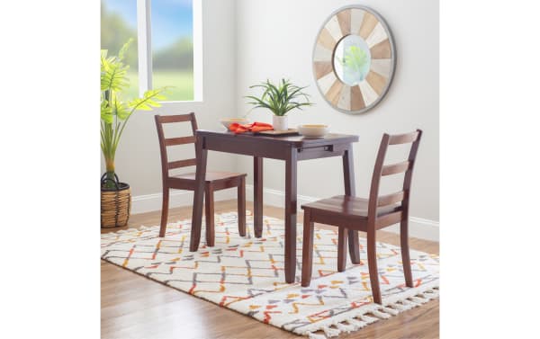 Brendon 3 Piece Brown Folding Solid Wood Dining Set with two ladder-back chairs and fold-flat table in traditional style. Made of steel, MDF, plywood, rubberwood solids, and paper veneer. Features hidden under-table storage for placemats and cutlery. Perfect compact dining for small spaces or studio apartments.