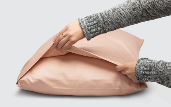 Hands adjusting a blush pink MyBob's King Blush Cozy Cotton 2 Piece Pillowcase Set in traditional style, made of soft, breathable 100% cotton fabric.
