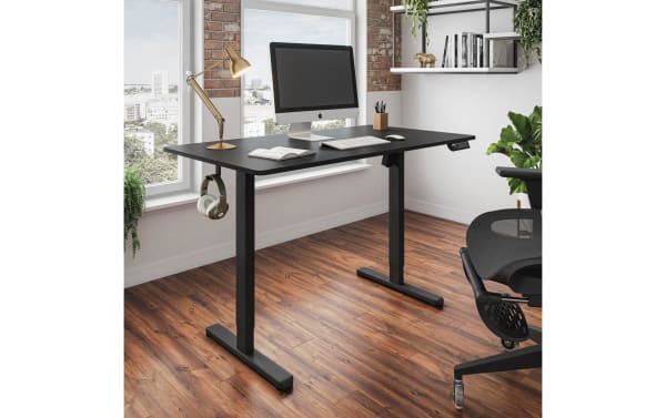Contemporary Ailyn Black 47.25'' Adjustable Height Desk with particle board top and steel frame, featuring electric lift with 3 memory presets, shown in modern office setup with monitor, lamp, headphones, and ergonomic chair on wood flooring.