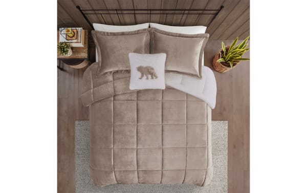 Taupe velvet comforter set on a bed with matching pillow shams, a white sherpa throw blanket, and a decorative white pillow with a bear design.