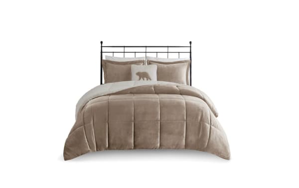 Taupe velvet comforter set on black metal bed frame, featuring plush quilted design, matching pillows, and a decorative bear-themed throw pillow.