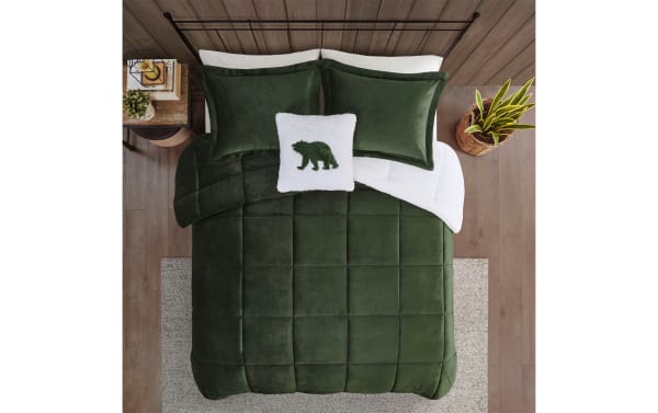 Dark green velvet comforter set on a bed with matching pillow shams and a white throw pillow featuring a green bear silhouette, styled in a rustic bedroom.