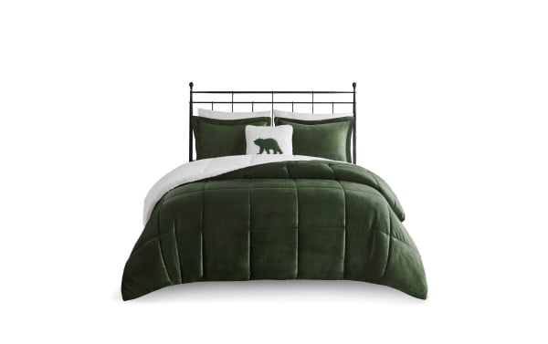 Dark green velvet comforter set with sherpa lining, matching pillow shams, and decorative bear accent pillow on black metal bed frame.