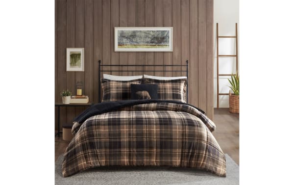 Cozy bedroom with a black metal bed frame, plaid brown and black bedding set, black throw blanket, wooden wall, and minimalist decor.