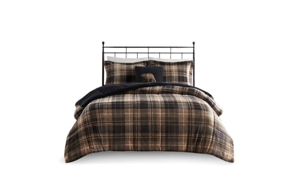 King-size bed with black metal frame, dressed in brown and black plaid comforter set, matching pillow shams, and a black decorative pillow with bear embroidery.