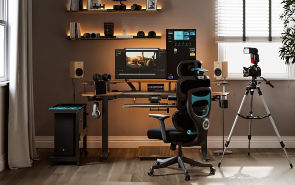 Modern home office setup with dual monitors, ergonomic black and blue office chair, DSLR camera on tripod, and wooden desk with speakers and headphones.
