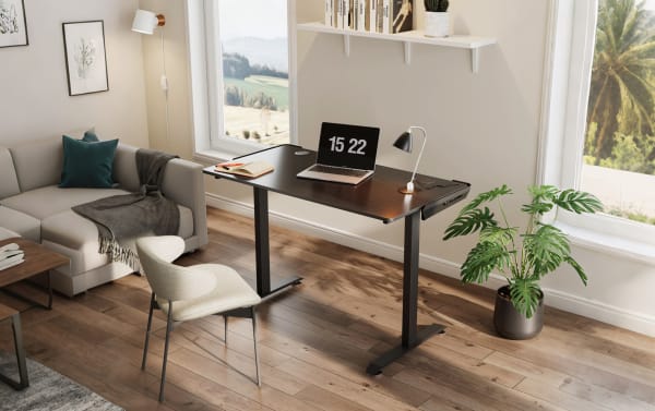 Aurora Black Adjustable Gaming Desk with carbon-fiber textured particle board top, powder-coated metal frame, dual cable holes, and built-in socket holder in a transitional home office setting.