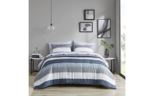 Santos Queen Blue 7 Piece Striped Comforter Set in polyester fabric features contemporary blue, light blue, gray, and white horizontal stripes with matching pillow shams, styled in a modern bedroom setting.