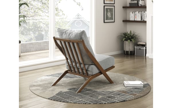 Silas Gray Accent Chair with mid-century modern rubberwood frame, gray chenille fabric upholstery, high-density foam cushion, and removable back pillow on a round patterned rug.