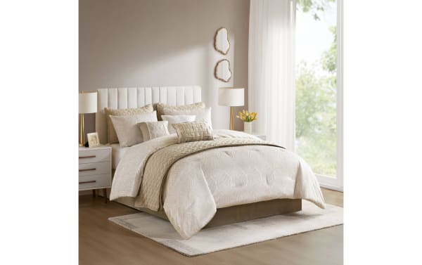 Beige and cream textured bedding set on a modern upholstered bed with vertical channel tufted headboard, paired with matching pillows and a cozy quilt in a bright bedroom with natural light.