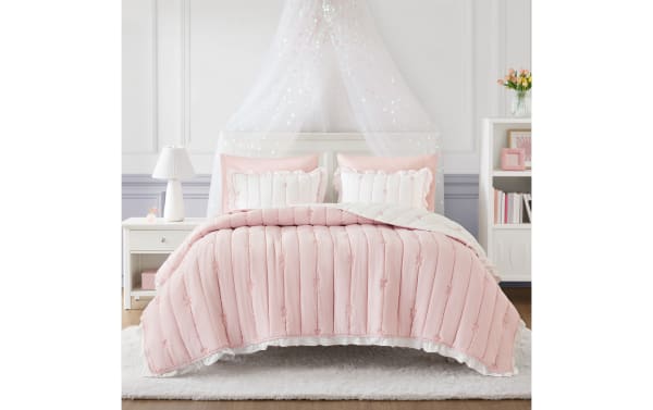 Maison Full/Queen Pink 3 Piece Quilt Set with soft pink and white microfiber, embroidered bows, ruffled edges, and down-alternative loft for cozy, contemporary style.