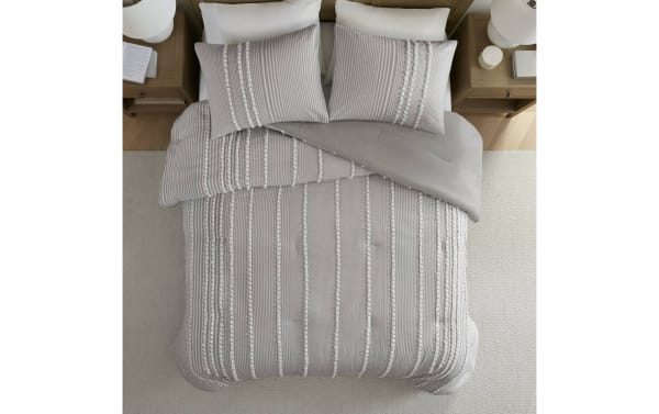 Gray textured comforter set with vertical tufted stripes and matching pillow shams on a bed, featuring a soft, cozy fabric and modern design.