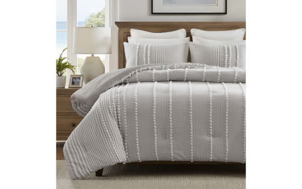 Gray and white striped tufted cotton comforter set on wooden bed with matching pillows, featuring textured vertical stripes for a cozy bedroom decor.