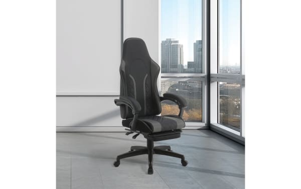 Black ergonomic gaming chair with high backrest, padded armrests, and adjustable height on caster wheels, set in a modern office space.