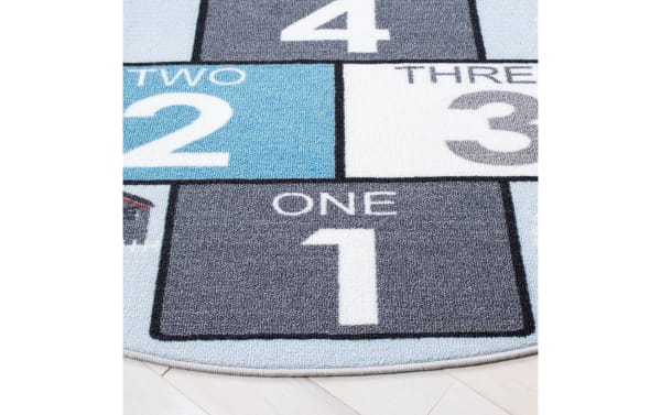 Happy Hopper 3' round light blue transitional rug with playful road and number blocks in gray, white, soft polyamide fabric, slip-resistant backing.