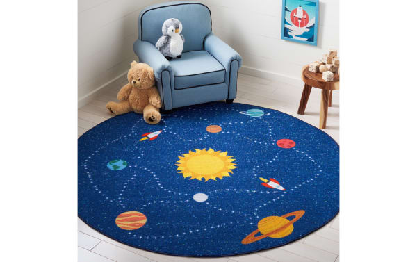 Orbit Adventure 3' round blue rug with a playful solar system design in navy, yellow, red, and orange. Made of durable polyamide fabric, this transitional kids' area rug is washable, smooth, and safe for playrooms and bedrooms.