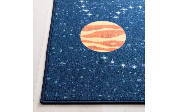 Dark blue space-themed rug with an orange planet and scattered stars, featuring a textured woven material and stitched edges.