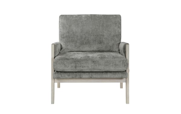 Gray upholstered armchair with plush cushions, whitewashed wooden frame, and mid-century modern design, ideal for living room seating.