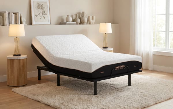Adjustable bed with white textured mattress labeled "BOBOPEDIC COPPER SPORT Hybrid" in a modern bedroom, featuring wooden side tables and lamps.