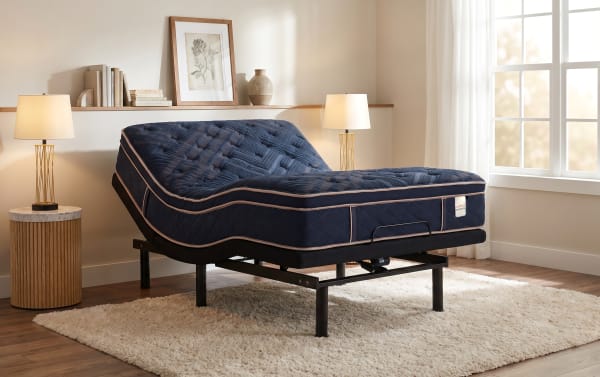 Adjustable navy blue Copper Radiance mattress on a black metal frame, set in a modern bedroom with wooden flooring, beige walls, and soft lighting.