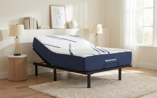Adjustable bed frame with a blue and white BOBOPEDIC Signature Hybrid mattress in a modern bedroom setting with wooden floors and neutral decor.