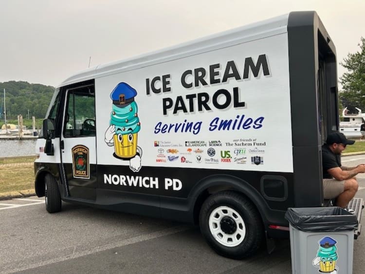 Black and white Norwich Police Department van with "ICE CREAM PATROL serving smiles" text and a cartoon ice cream cone wearing a police hat on the side.
