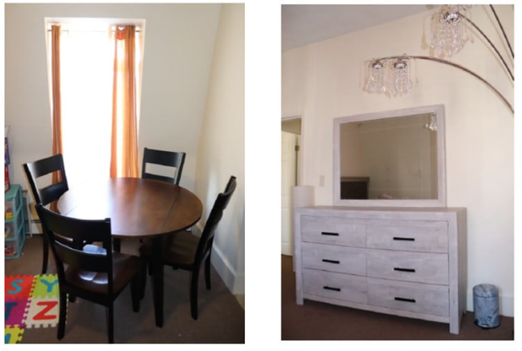 Dining area with a round wooden table and four black chairs near a window with orange curtains; adjacent bedroom dresser with a large mirror and crystal chandelier lighting.