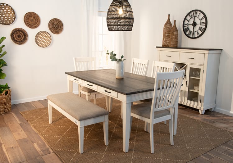 Dining room set with a dark wood rectangular table, white wooden chairs with beige cushions, and a matching bench on a brown patterned rug.
