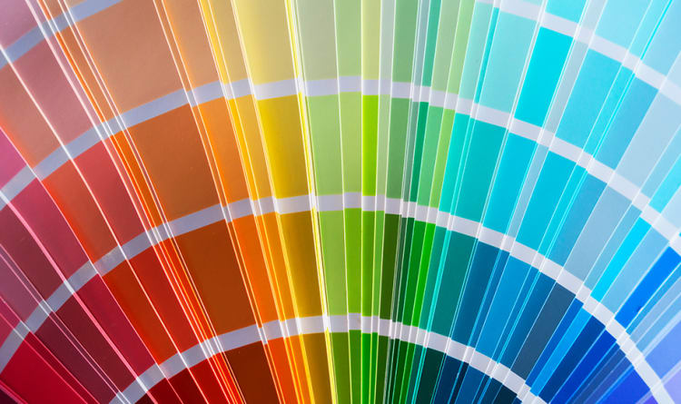 A fan of paint color swatches arranged in a gradient from red to blue, showcasing a wide range of vibrant hues for design and decoration choices.