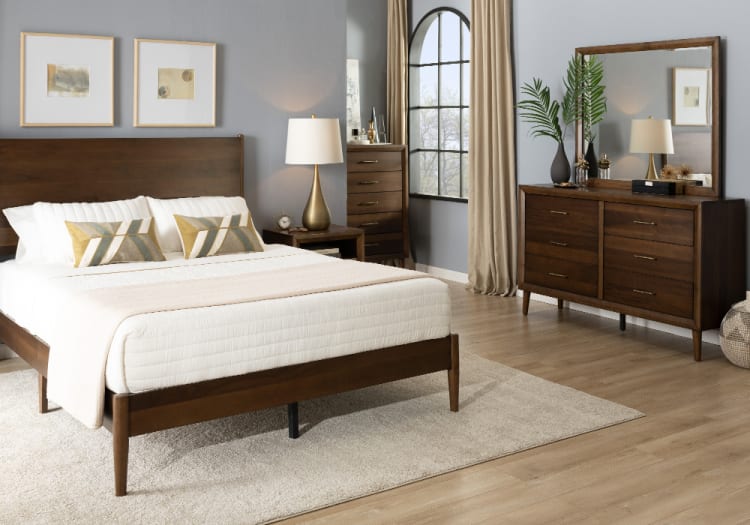 Modern bedroom with dark wood mid-century style bed frame, white bedding, beige throw, matching dresser with mirror, and gold-accented lamps.