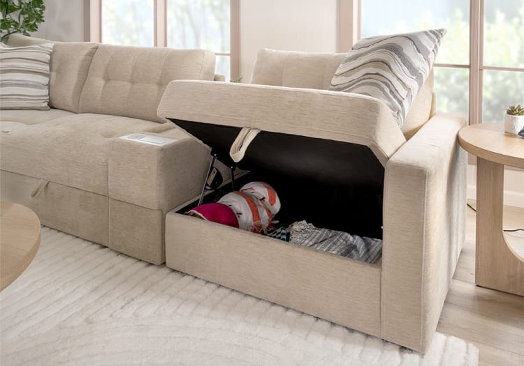 Beige fabric sectional sofa with storage compartment under the armrest, featuring a striped cushion and soft textured upholstery in a bright living room.