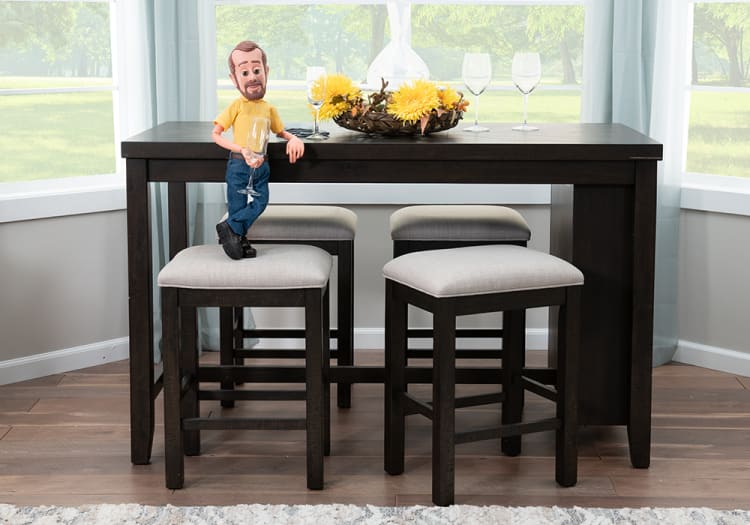 Dark wood dining table with four matching cushioned stools, beige upholstery, decorative yellow flowers centerpiece, and empty wine glasses.