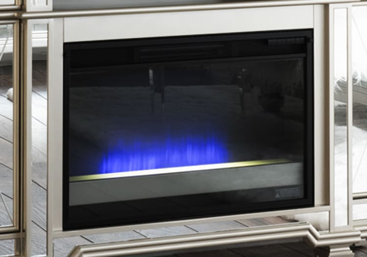 Electric fireplace with blue LED flame effect, black glass front, and silver frame, installed in modern living room setting.