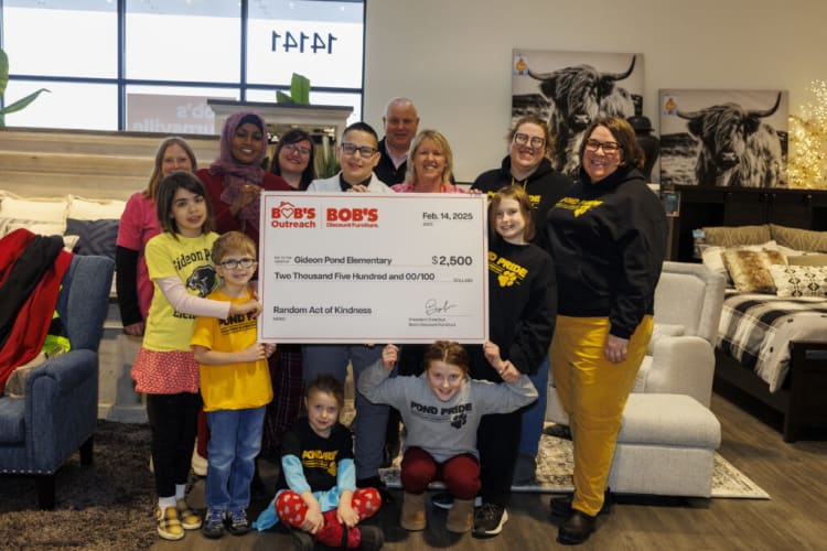 Group holding a large $2,500 donation check from Bob's Discount Furniture to Gideon Pond Elementary for Random Act of Kindness, dated Feb. 14, 2025.