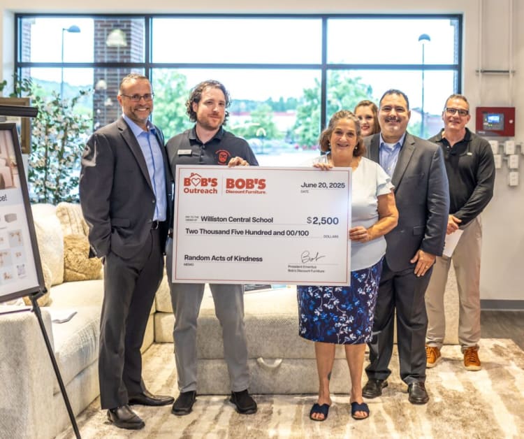 Group of five people holding a large check from Bob's Discount Furniture dated June 20, 2025, for $2,500 to Williston Central School for Random Acts of Kindness.
